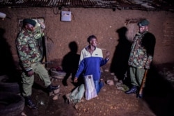 Security officers arrests a man selling alcohol door to door during curfew hours in Kisumu, western Kenya, March 29, 2020.
