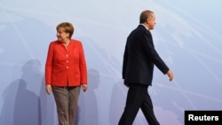 FILE - German Chancellor Angela Merkel and Turkey President Recep Tayyip Erdogan go their separate ways after a handshake greeting at the beginning of the G20 summit in Hamburg, Germany, July 7, 2017.