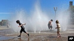 Children play in a fountain to cool off in downtown Portland, Oregon, May 12, 2023.