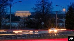 A car moves along U.S. Highway 50 early in the morning, March 30, 2018, across the Potomac River from Washington in Arlingotn, Virginia. The Trump administration is expected to announce that it will roll back automobile gas mileage and pollution standards that were approved during the Obama administration.