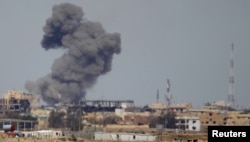 FILE - A plume of smoke rises above a building after an airstrike by the U.S.-led coalition battling the Islamic State group, in Tikrit, Iraq, March 27, 2015.