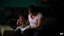 Lucia, 38, from Guerrero state, draws with her youngest daughter as she and her children wait at Agape World Mission shelter for a chance to request asylum in the United States, in Tijuana, Mexico, Friday, Sept. 13, 2019.