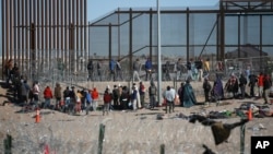 Migrantes formados después de ser detenidos por las autoridades migratorias de Estados Unidos en el muro fronterizo, el miércoles 27 de diciembre, captados desde Ciudad Juárez, México.