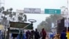 Congolese people walk near the gate barriers at the border crossing point with Rwanda following its closure over Ebola threat in Goma.
