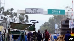 Congolese people walk near the gate barriers at the border crossing point with Rwanda following its closure over Ebola threat in Goma.