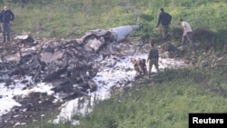 Israeli security forces walk next to the remains of an F-16 Israeli warplane near the Israeli village of Harduf, Israel, Feb. 10, 2018. 