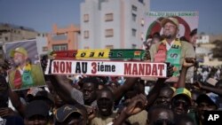 Un homme brandit une pancarte sur laquelle on peut lire en français "Non au troisième mandat" lors d'une manifestation à Dakar, au Sénégal, le 12 mai 2023.