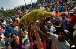 Supporters of Zimbabwe's President in waiting Emmerson Mnangagwa, known as "The Crocodile", raise a stuffed crocodile in the air as they await his arrival at the Zanu-PF party headquarters in Harare, Zimbabwe, Nov. 22, 2017.