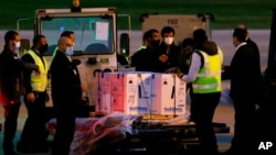 Workers stand next to boxes of the first shipment of the Pfizer-BioNTech vaccine for COVID-19 after it arrived at the Rafik Hariri International Airport in Beirut, Lebanon, Feb. 13, 2021. 