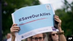 A woman holds high a sign that reads "#SaveOurAllies" at a rally calling for the evacuation of Afghan allies, July 1, 2021.