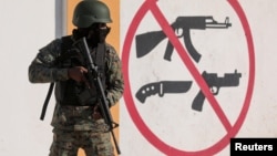 A soldier stands guard next to a sign prohibiting the use of weapons outside the military headquarters as Haiti continues in a state of emergency, in Port-au-Prince, Haiti, March 6, 2024.