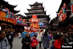 People walk by a giant decoration in the shape of a pig ahead of the upcoming Chinese Lunar New Year in Yu Yuan Garden in Shanghai, China, Jan. 31, 2019.