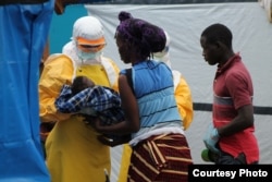 A Doctors Without Borders (MSF) staff member receives a young patient at the Ebola management center in Foya, Liberia. (Courtesy photo by Martin Zinggl/MSF)