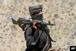 FILE - In this May 27, 2016 file photo, a member of a breakaway faction of the Taliban fighters guards a gathering in Shindand district of Herat province, Afghanistan.