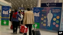 Travelers pass by a health checkpoint before entering immigration at the international airport in Beijing, Jan. 13, 2020. 