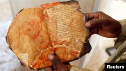 A museum guard displays a burned ancient manuscript at the Ahmed Baba Institute, or Ahmed Baba Center for Documentation and Research, in Timbuktu, Mali, Jan. 31, 2013.