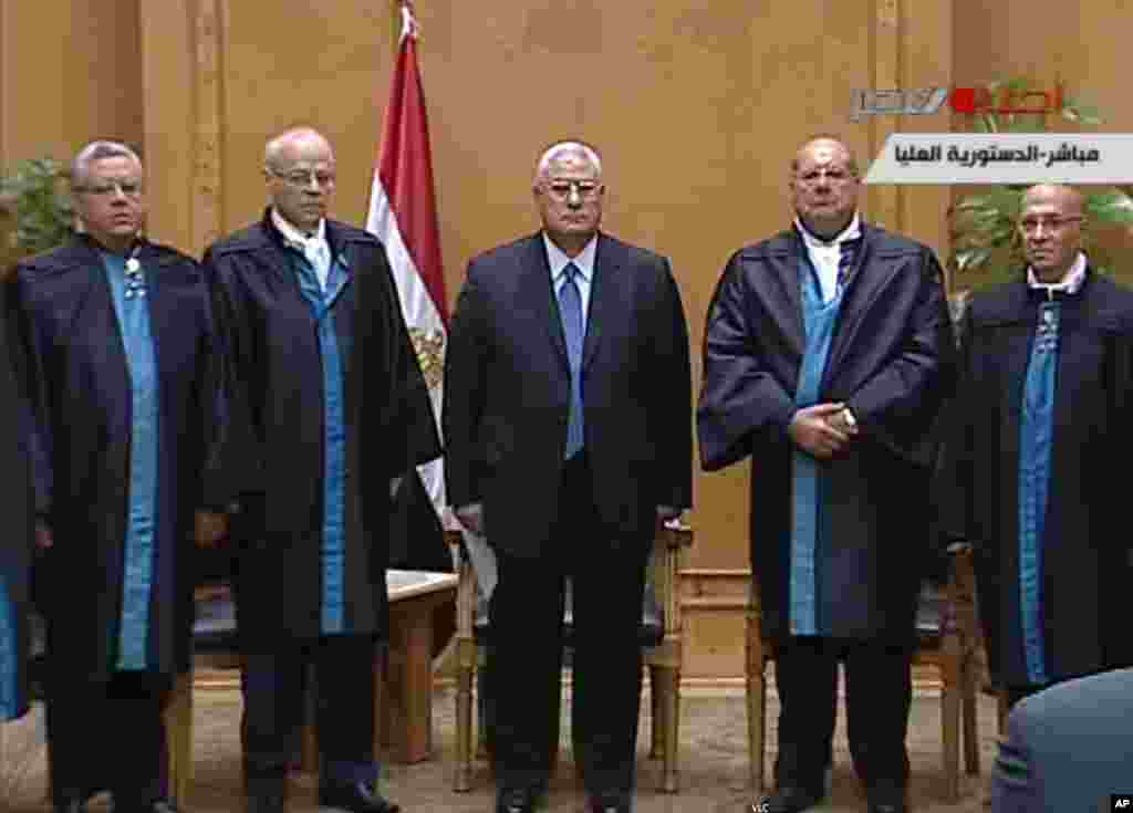 This image made from Egyptian State Television shows Egypt's interim president Adly Mansour, center, standing with judges during a swearing in ceremony at the constitutional court in Cairo, July 4, 2013.