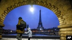 ARCHIVO - La Torre Eiffel vuelve a recibir visitantes después de varios días de cierre por reclamos del sindicato de trabajadores. En la imagen, un niño y su cuidador caminan con la mayor atracción francesa de fondo, el 18 de enero de 2024, después de una nevada.