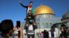 Pemuda Palestina berpose dengan Kubah Batu terlihat di latar belakang, saat shalat Idulfitri di kompleks Masjid al-Aqsa di Kota Tua Yerusalem, di tengah pertempuran Israel-Gaza, 13 Mei 2021. (Photo: REUTERS/Ammar Awad)