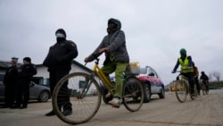 Vietnamese workers who are helping construct the first Chinese car tire factory in Europe ride bicycles past security officers near the northern Serbian town of Zrenjanin, 50 kilometers north of Belgrade, Nov. 18, 2021.