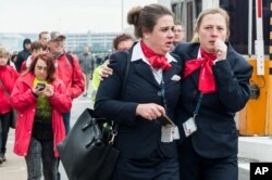 People react as they walk away from Brussels airport after explosions rocked the facility in Brussels, Belgium, March 22, 2016.