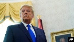 FILE - President Donald Trump listens to a reporter's question at an event in the Oval Office of the White House, in Washington, Dec. 7, 2020.