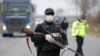 FILE - Police officers check motorists on a road access point to Tandarei, eastern Romania, April 4, 2020, after authorities imposed a severe quarantine status on the city.