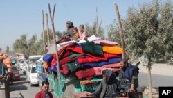 FILE - Afghan families leave their houses after fighting between the Afghan military and Taliban insurgents in Helmand province, Afghanistan, Oct. 13, 2020.