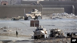 A destroyed military armored vehicle, right, belonging to Polish soldiers with the NATO led International Security Assistance Force (ISAF) is seen at the scene after it was hit by a road side bomb in Ghazni, southwest of Kabul, Afghanistan, December 21, 2