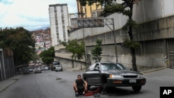 Un hombre se sienta en medio de la carretera junto a su automóvil averiado en el barrio de Petare, Caracas, Venezuela. Febrero 6, 2021.