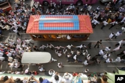FILE - Mourners march along the decorated vehicle loaded with the body of Cambodian prominent political analyst Kem Ley during a funeral procession in Phnom Penh, Cambodia.
