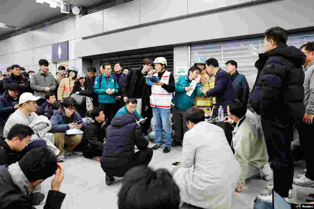 People listen as an official discloses the additional names of passengers who died in the plane crash at Muan International Airport, Dec. 29, 2024.