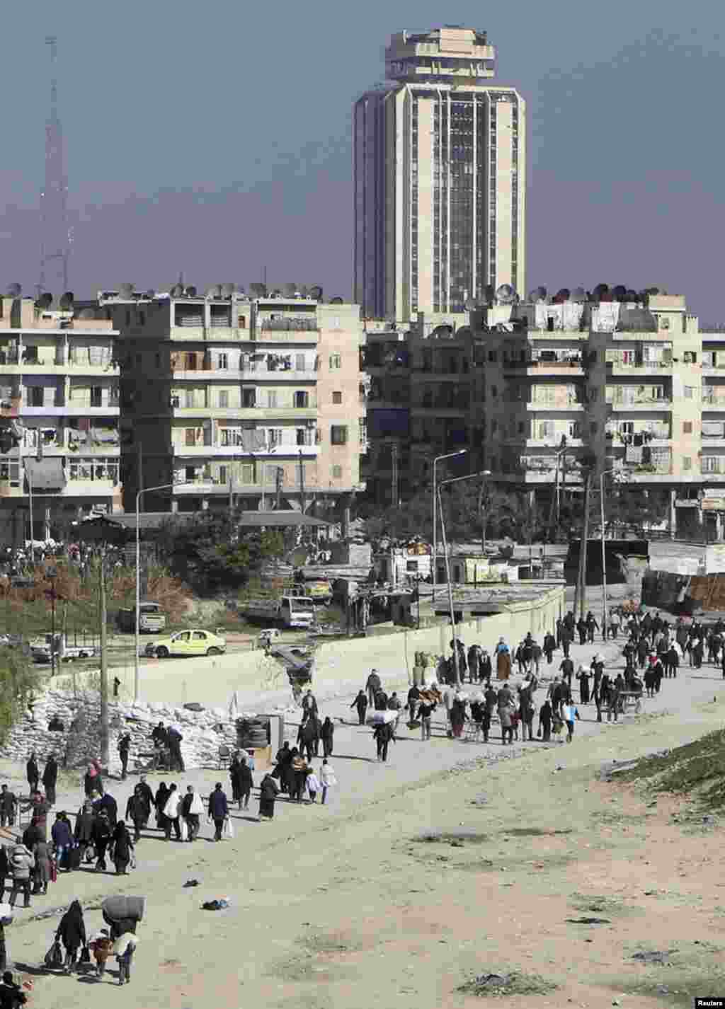 Civilians carry their belongings as they walk at the Karaj al-Hajez crossing, a passageway separating the Bustan al-Qasr district, which is under the rebels&#39; control and the Al-Masharqa district, an area controlled by the Assad regime, Aleppo, Feb. &nbsp;9, 2014.&nbsp;