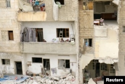 FILE - Children stand on a balcony of a damaged building at a site hit at dawn by an airstrike in the rebel-controlled town of Ariha in Idlib province, Syria, Feb. 27, 2017.