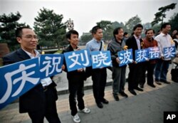Supporters of Liu Xiaobo hold cards that read "We celebrate Liu Xiaobo winning the Nobel Prize" outside a park in Beijing, China, 08 Oct. 2010
