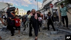 Palestinian families rush out of their homes after Israeli airstrikes targeting their neighborhood in Gaza City, central Gaza Strip, Oct. 17, 2023.