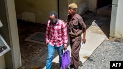Tanzanian journalist Erick Kabendera (L) leaves the prison where he had been held for several months on Feb. 24, 2019 in Tanzania, freed after pleading guilty to economic crimes. 