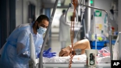 A medical staff member speaks with a COVID-19 patient in the infectious disease ward of the Strasbourg University Hospital, eastern France, Jan. 13, 2022.