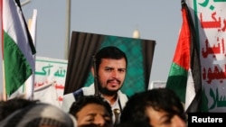 A person holds a placard with a picture of Yemen's Houthi movement leader, Abdul-Malik al-Houthi, as supporters rally to denounce airstrikes launched by the U.S. and Britain on Houthi targets, in Sanaa, Yemen, on Jan. 12, 2024.