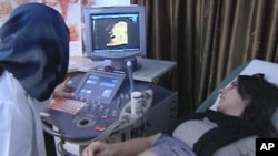 Dr. Mutahar Fauzia (L) uses an ultrasound machine to check on the development of Laiqa Ahmed's unborn child