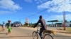 FILE - A man cycles along a street past a gas station in Macomia, Cabo Delgado province, Northern Mozambique, June 11, 2018.