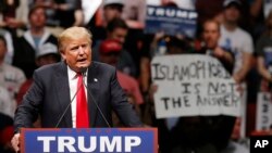 FILE - Republican presidential candidate Donald Trump speaks at a rally as a man holds up a sign that reads "Islamophobia is not the answer" in Oklahoma City, Feb. 26, 2016.