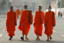 Buddhist monks wear masks as they walk near Royal Palace in Phnom Penh, Cambodia, Jan. 28, 2020.