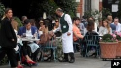 A waiter serves in a restaurant in Covent Garden in London, Sept. 22, 2020.