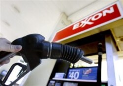 FILE - A customer holds a gas pump handle at an Exxon station in Vancouver, Wash.
