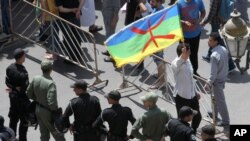 Un homme brandit un drapeau amazigh devant des policiers lors d'une manifestation contre la corruption gouvernementale et les abus officiels du pouvoir à Rabat, au Maroc, 11 juin 2017.