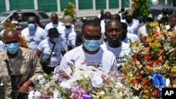 Pierre Gary Bernadotte, a member of the slain president's PHTK political party, carries flowers to a spot outside the presidential palace in memory of the late President Jovenel Moise in Port-au-Prince, Haiti, July 14, 2021.