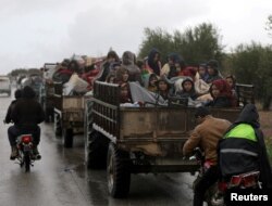 Fleeing civilians sit in the cargo hold of a vehicle with their belongings, northeast of Afrin, Syria, March 15, 2018.