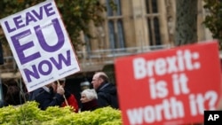 FILE - Pro- and anti-Brexit protesters hold placards as they vie for media attention near Parliament in London, Nov. 16, 2018. Britain's Prime Minister May still faces the threat of a no-confidence vote, after several Conservative Party lawmakers said they had wr