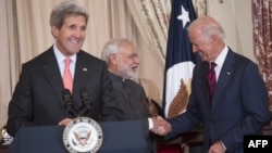 Menlu AS John Kerry berbicara pada acara di Deplu AS sementara Wapres AS Joe Biden berjabat tangan dengan PM India Narendra Modi, di Washington, DC, 30 September 2014.